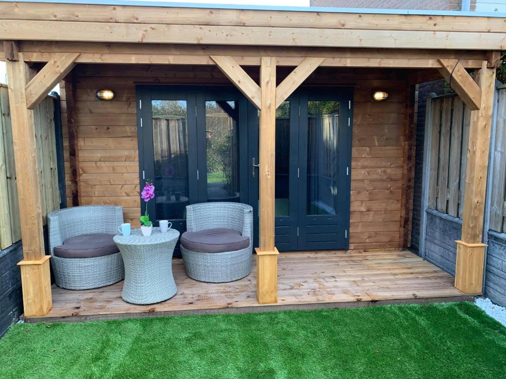 a wooden pergola with chairs and a table at Chalet - B&B de Koog in Uitgeest