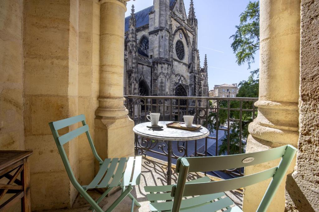 une table et des chaises sur un balcon avec une église dans l'établissement Centre historique, appartement climatisé avec terrasse, à Bordeaux
