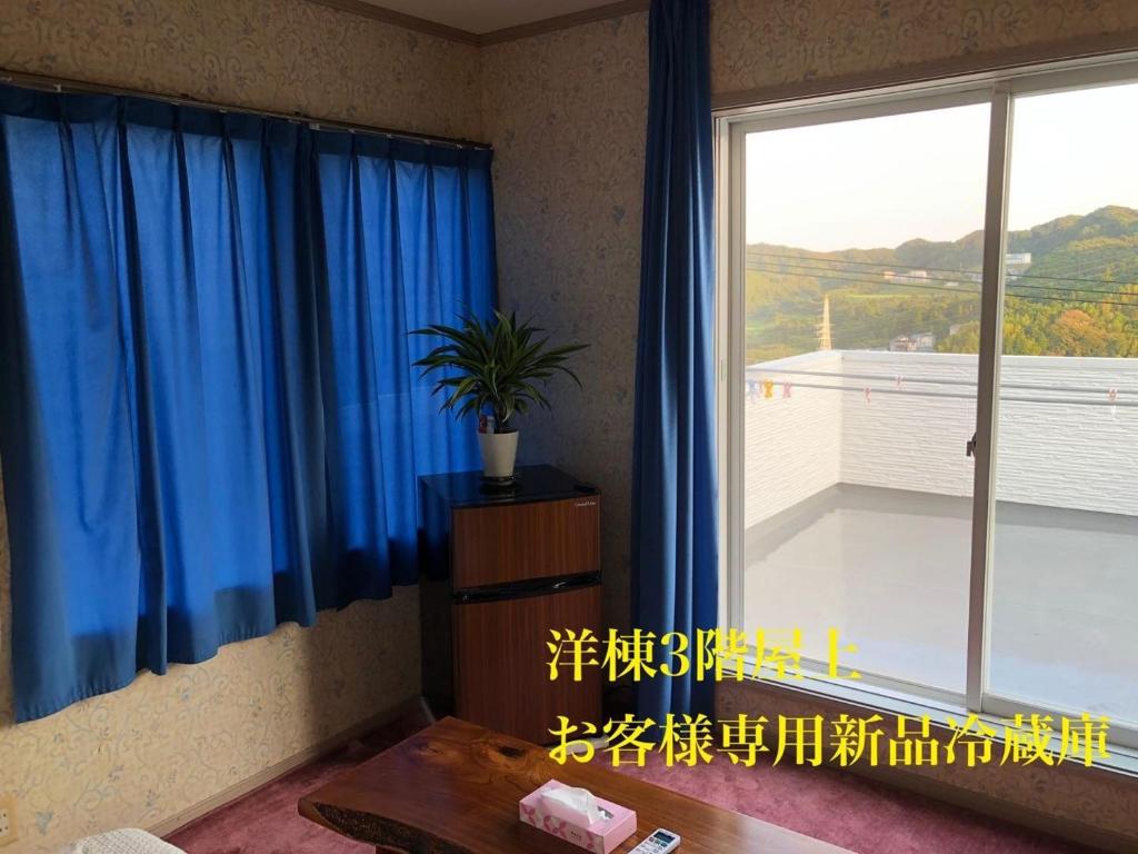 Zimmer mit einem großen Fenster und blauen Vorhängen in der Unterkunft Kamogawa - House - Vacation STAY 9979 in Kamogawa