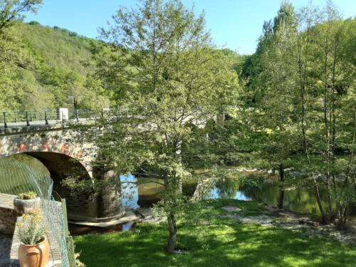 een brug over een waterlichaam met een rivier bij Auberg'IN ! in La Salvetat-Peyralès