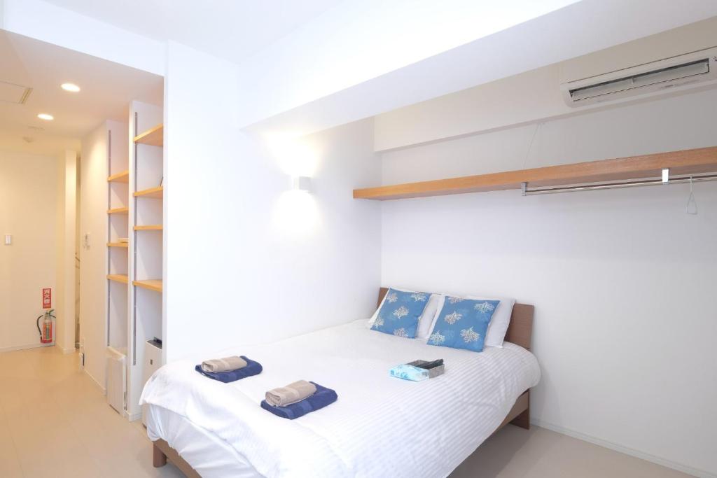 una camera bianca con letto e scaffali di Good Life Apartment - Vacation STAY 08485v a Naha