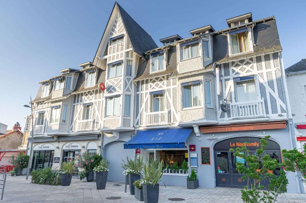 a large building with white trim on a street at Cit'Hotel Normandy Hotel Pornichet La Baule in Pornichet