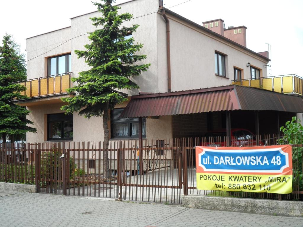 a building with a sign in front of a fence at Kwatery Pokoje Mira in Poznań