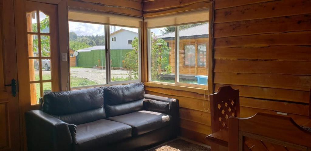 un sofá de cuero en una habitación con ventanas en Turismo Don Hugo, en Puerto Tranquilo
