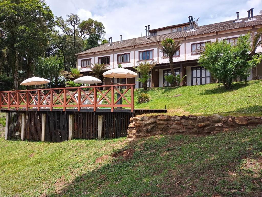 una casa con un puente con sombrillas delante en Pousada VillaSerrana en Monte Verde