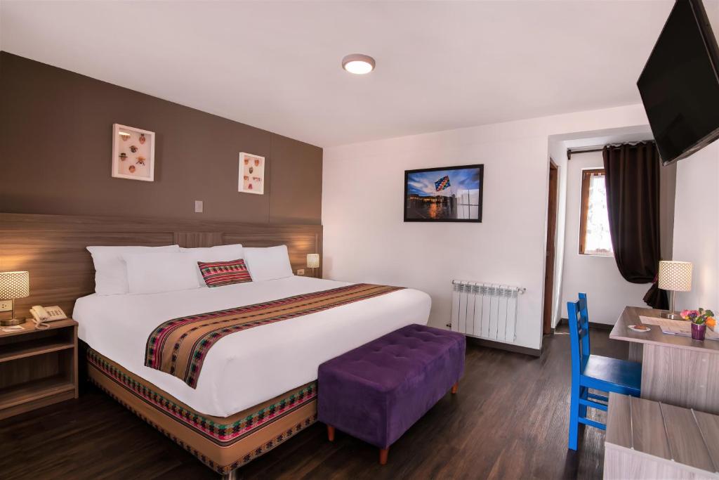 a hotel room with a large bed and a purple stool at Atoq San Blas Hotel in Cusco