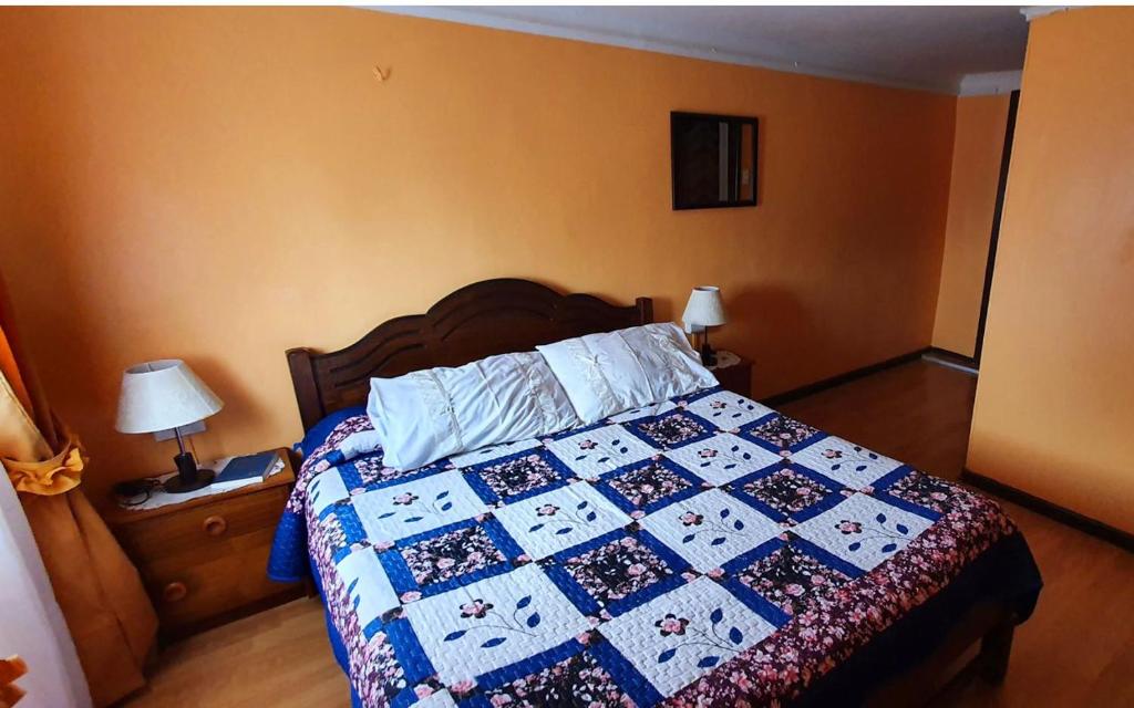 a bedroom with a bed with a quilt on it at Hotel Iberia in Coquimbo