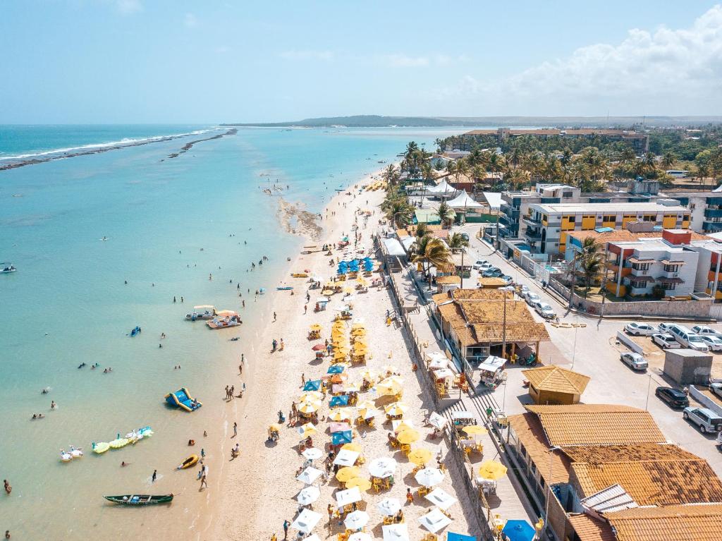 a beach with umbrellas and people in the water at Portal do Atlântico in Barra de São Miguel