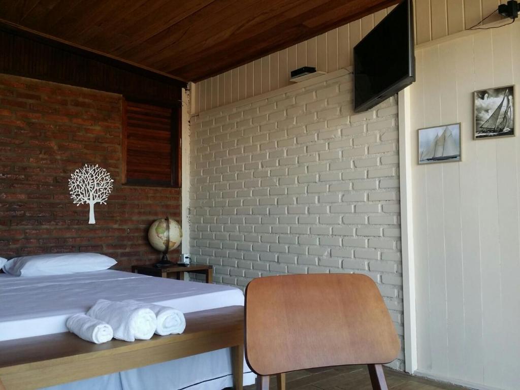 Un dormitorio con una cama con toallas blancas. en Hospedaria Rosa dos Ventos en Marataizes