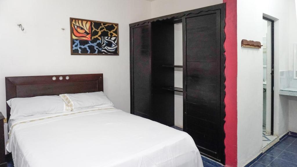 um quarto com uma cama branca e um armário preto em Hotel D´Concepción em Tizimín
