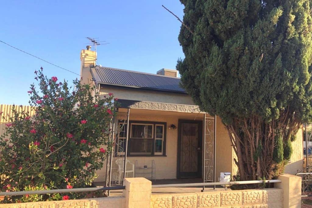 a house with two trees in front of it at Modern Charming Miners’ Cottage +Free Internet in Broken Hill