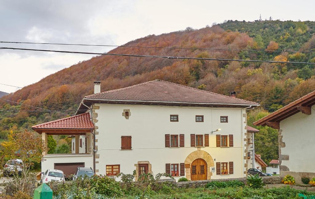 Une grande maison blanche avec une montagne en arrière-plan dans l'établissement Casa Rural Lenco, à Zilbeti