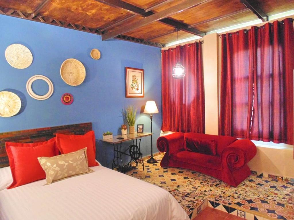 1 dormitorio con 1 cama y 1 silla roja en Suites Portal San Ángel al mejor precio, en Ciudad de México