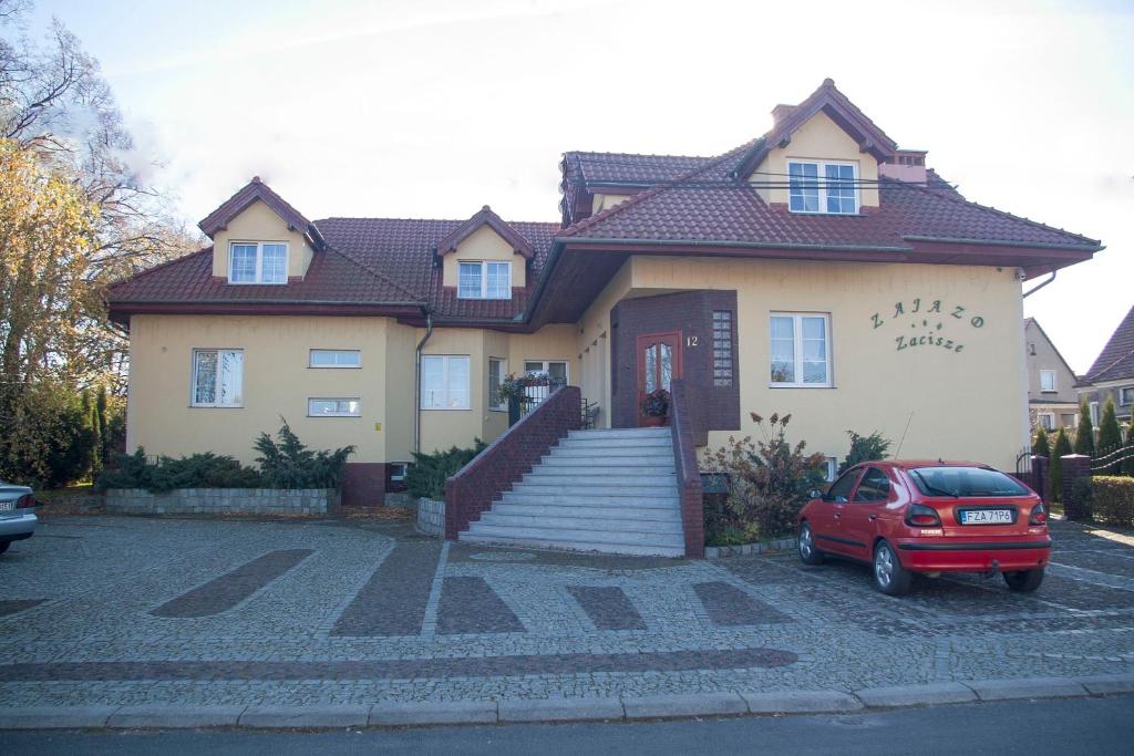 une maison avec une voiture rouge garée devant elle dans l'établissement Zajazd Zacisze, à Żary