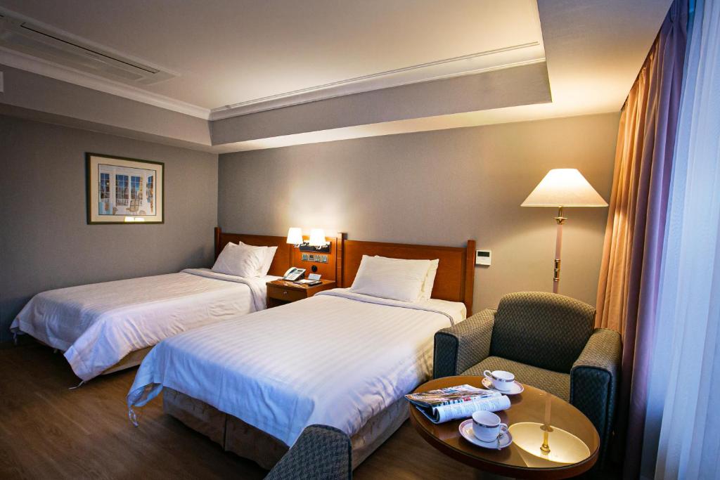Cette chambre comprend deux lits, une chaise et une table. dans l'établissement Hotel Paragon, à Busan
