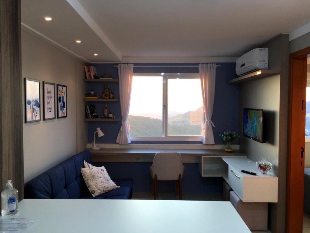 sala de estar con sofá azul y ventana en Apartamento aconchegante com vista para o vale dos vinhedos, en Bento Gonçalves
