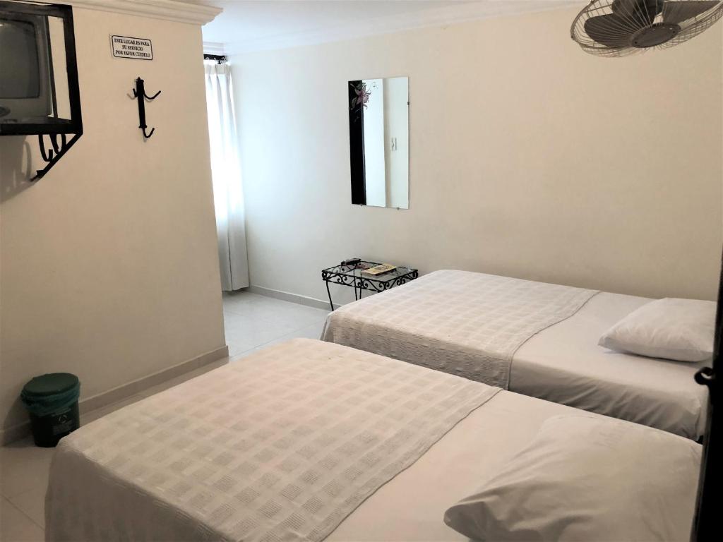 Habitación de hotel con 2 camas y TV en Hotel Central Johanna en Tuluá