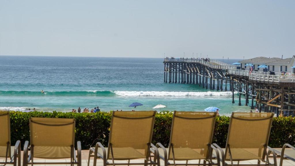 a group of chairs sitting next to a beach with a pier at Steps From The Sandy Pacific Beach in San Diego