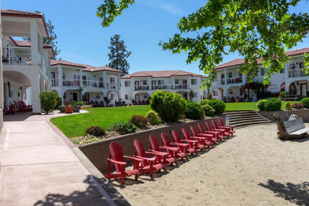 uma fila de cadeiras vermelhas na frente das casas em Sandy Beach Suites em Osoyoos