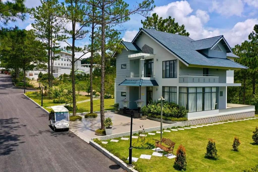 a white house with a car parked in the driveway at Thuy Hoang Nguyen Resort & Spa in Da Lat
