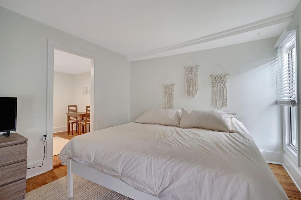 a white bedroom with a bed and a tv at The Melrose in Ocean Grove