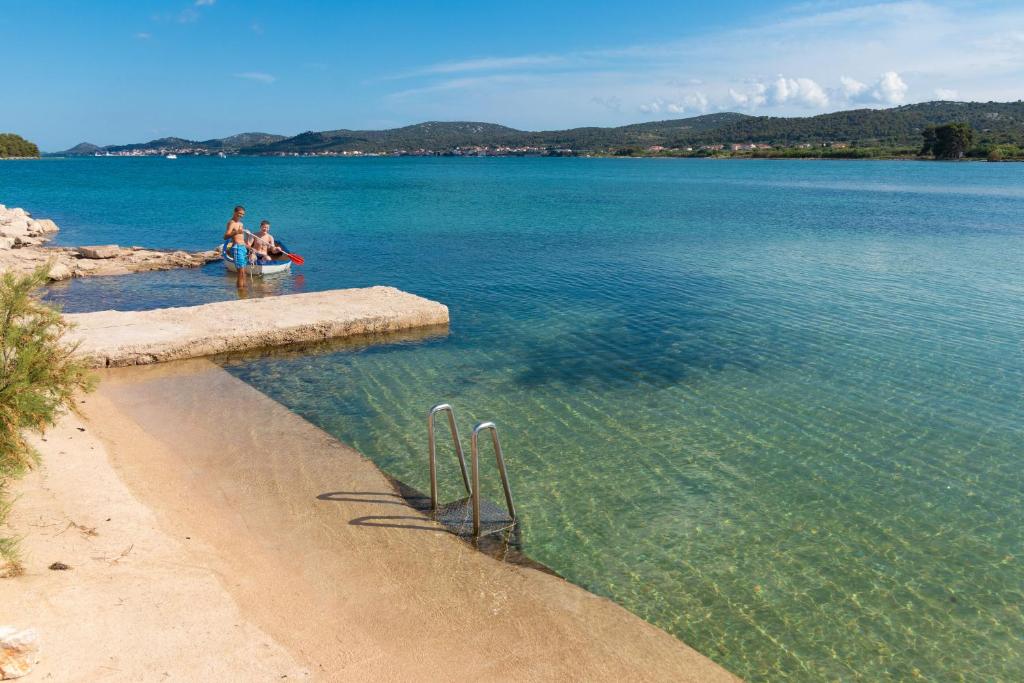two people sitting in the water on a beach at Mobile home Sea Bream in Pašman