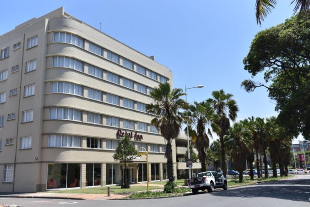 un bâtiment avec une voiture garée devant lui dans l'établissement Regal Inn North Beach, à Durban