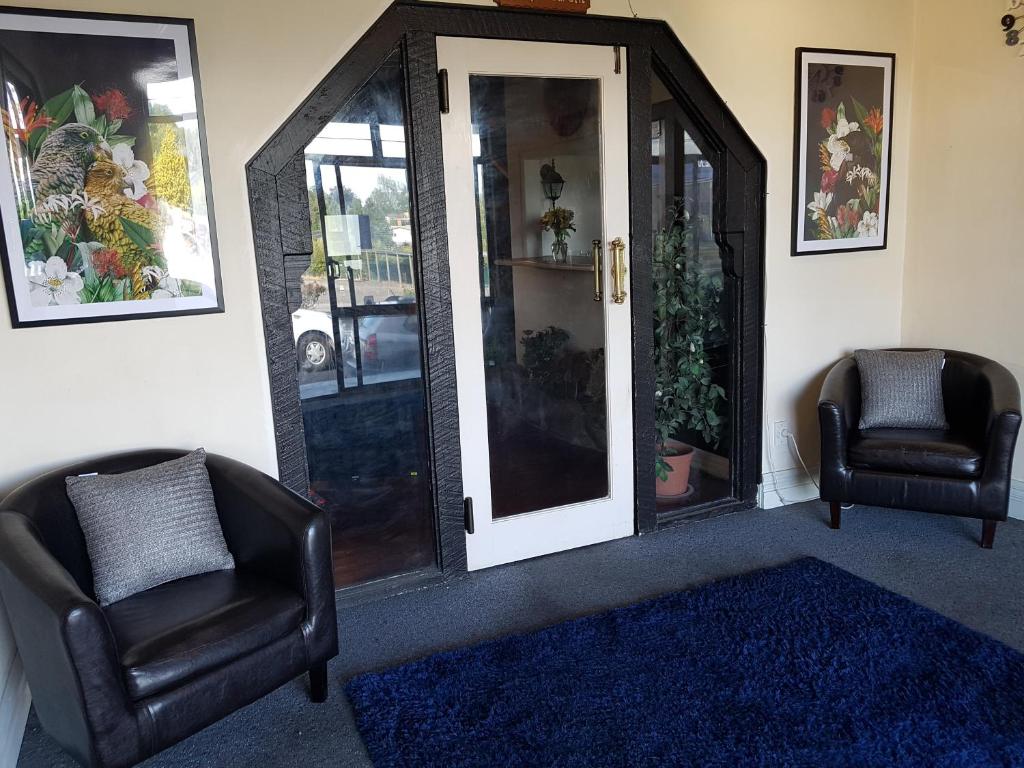a living room with two chairs and a glass door at Putaruru Arms Motor Inn in Putaruru