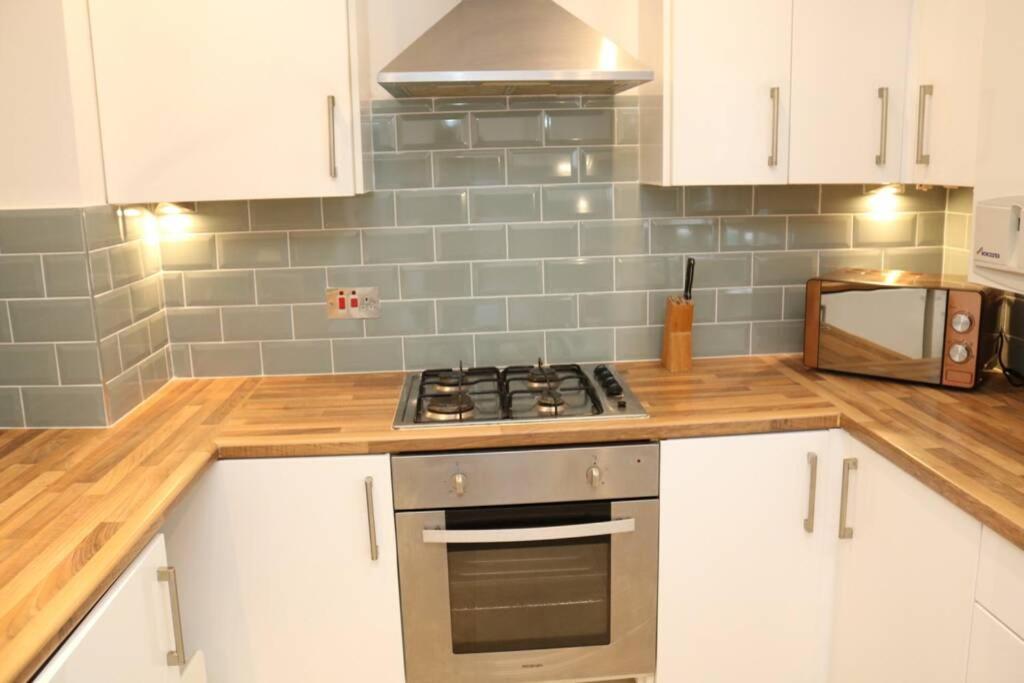 uma cozinha com armários brancos e um forno com placa de fogão em Large 3 bedroom apartment in gated development em Londres