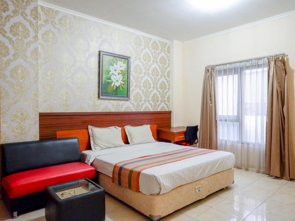 um quarto com uma cama e uma cadeira vermelha em Pineapple Mansion Solo Mitra RedDoorz near RS JIH Solo em Surakarta