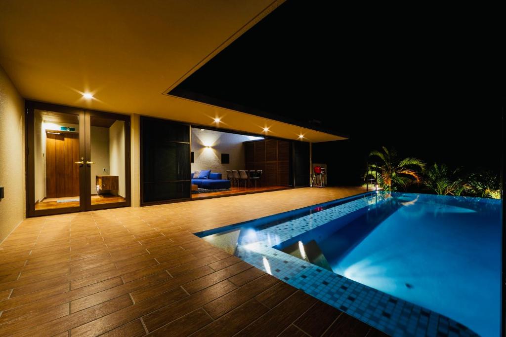 een zwembad in het midden van een huis 's nachts bij relax kouri villa Rekrrr in Nakijin