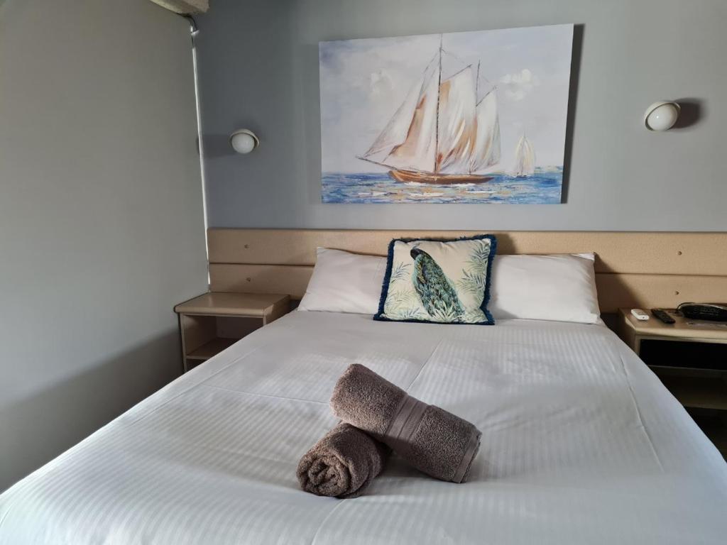 a bedroom with a white bed with a sailboat on it at Rockhampton Court Motor Inn in Rockhampton