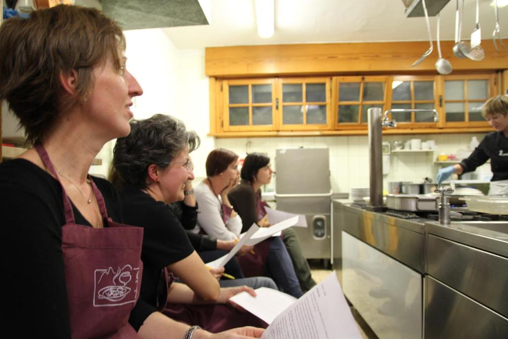 Un gruppo di donne sedute in cucina di Hotel 2 Camini a Baselga di Pinè