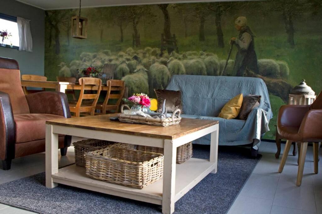 ein Wohnzimmer mit einem Sofa und einem Tisch in der Unterkunft De Schaapskooi - Knus Veluws vakantiehuisje in Ede