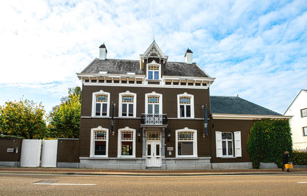 a large brown house with white windows on a street at Villa Tilia in Retie