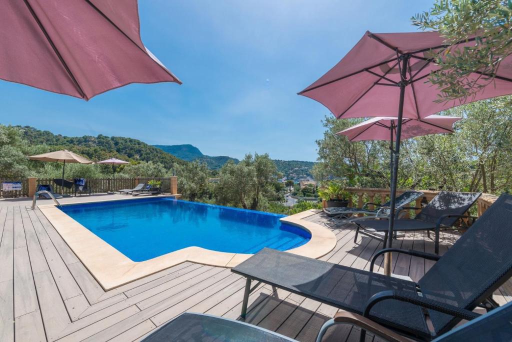 a swimming pool with chairs and an umbrella at Can Baixo in Port de Soller