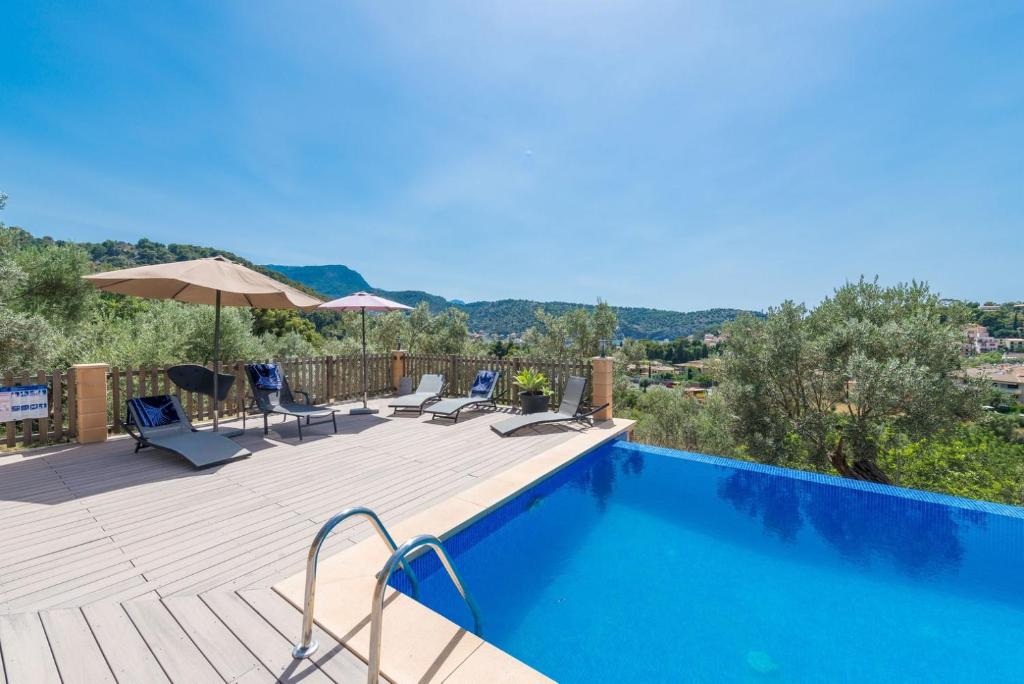 una piscina con sillas y una sombrilla en una terraza en Can Tamany, en Puerto de Sóller