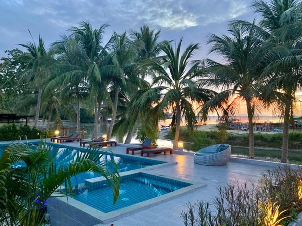 a resort with a swimming pool and palm trees at Breeze Bay Villa in Wok Tum