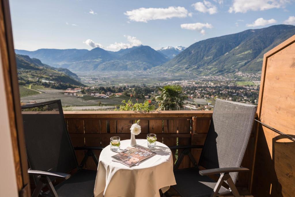 stół z 2 kieliszkami do wina na balkonie z widokiem na góry w obiekcie Pension zum Burggräfler w mieście Schenna