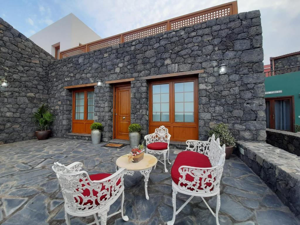 een patio met stoelen en een tafel voor een stenen gebouw bij Casa La Torera in Isora