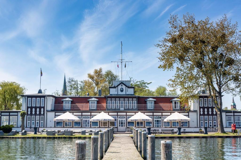 - un grand bâtiment à côté d'une étendue d'eau dans l'établissement Gästehaus am Schweriner See, à Schwerin