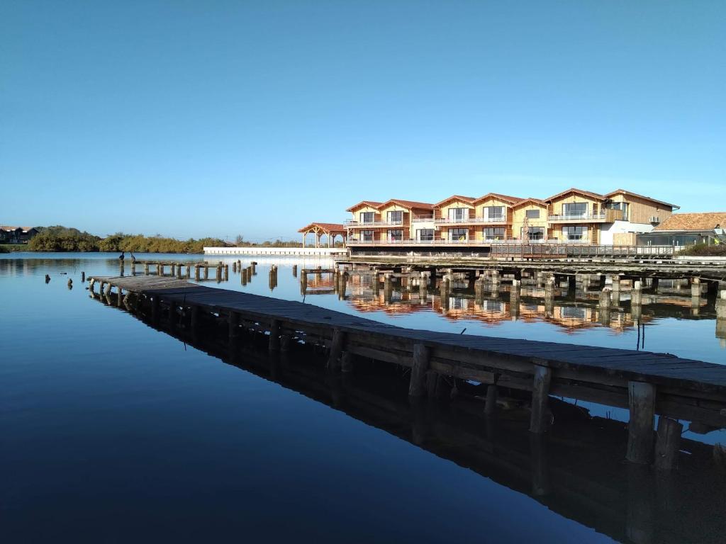 una fila de casas en un muelle sobre un cuerpo de agua en LES 12 DE LARROS, en Gujan-Mestras