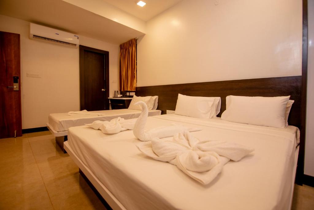 two beds in a hotel room with towels on them at Gopuram Residency in Madurai