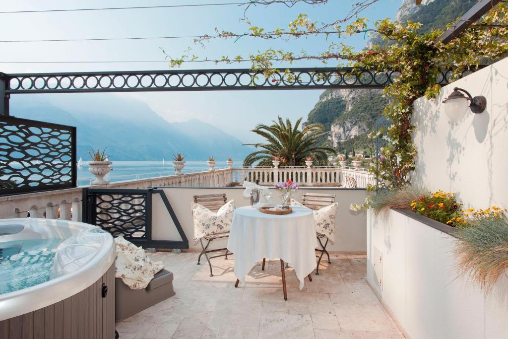 un patio con mesa y vistas a las montañas en Bellavista Lakefront Hotel & Apartments en Riva del Garda