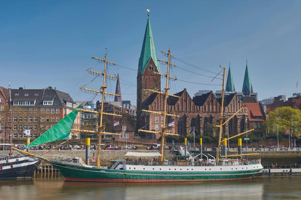 un bateau assis à l'eau devant une ville dans l'établissement Alexander von Humboldt - Das Schiff, à Brême