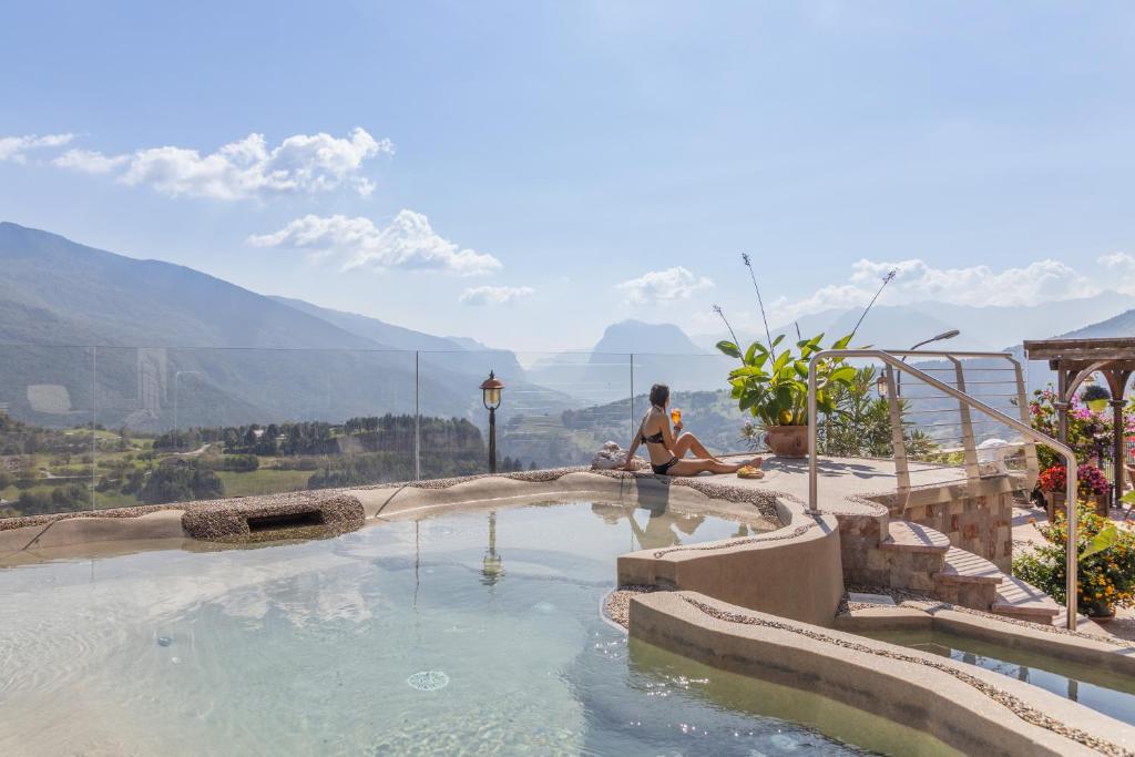 un hombre sentado junto a una piscina con vistas en Miravalle en San Lorenzo in Banale