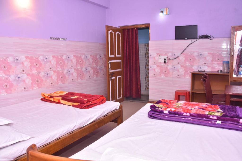 a room with two beds and a table and a tv at Milan Guest House in Digha