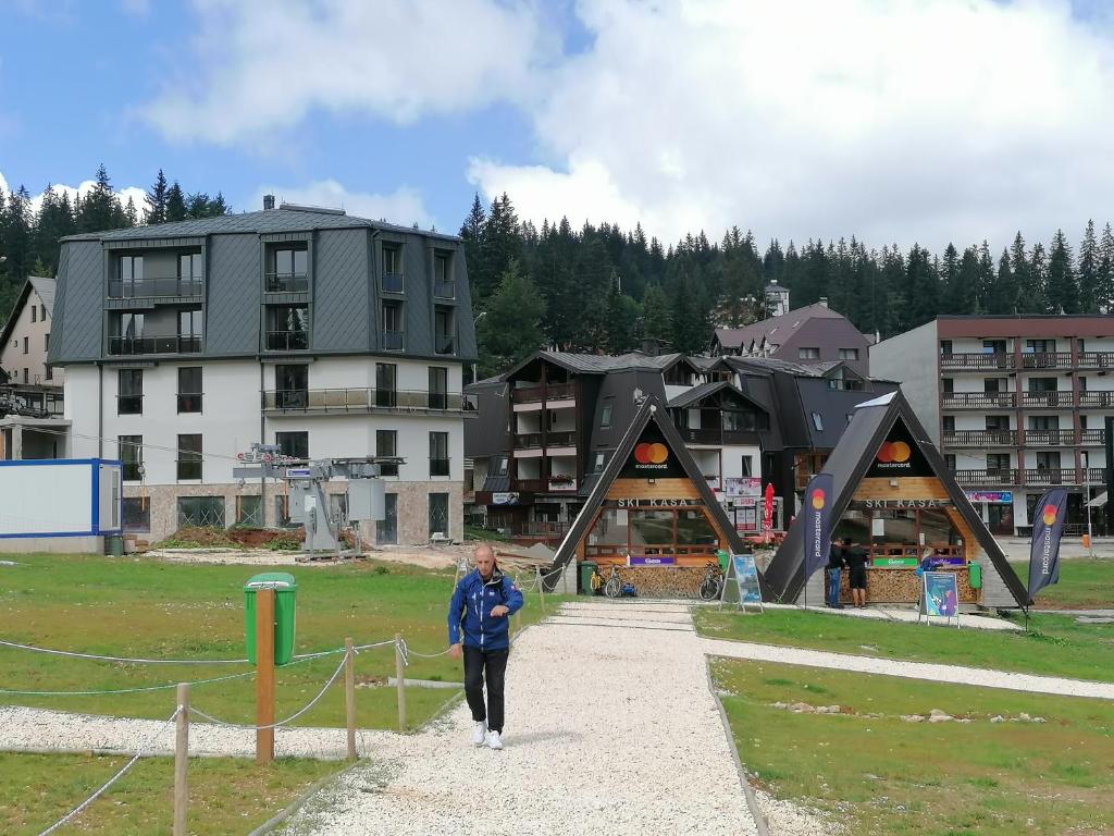 a woman walking down a path in front of a building at CENTRALA Jahorina in Jahorina