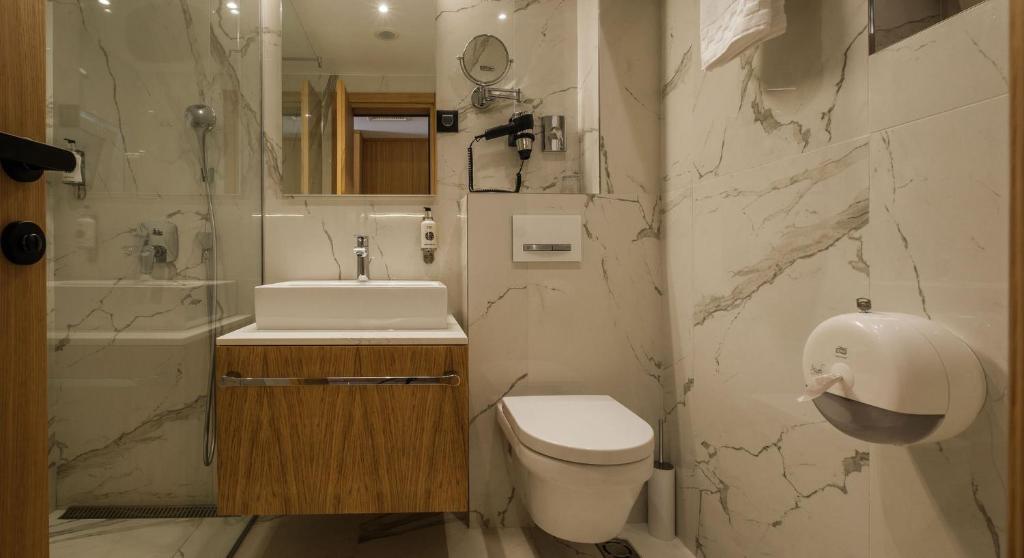 a bathroom with a toilet and a sink and a shower at Poseidon The Beach Hotel in Budva
