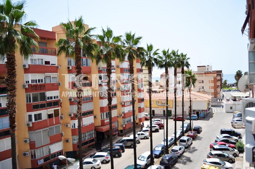 un aparcamiento con palmeras y edificios en Apartamentos Terrasol Plazamar, en Torre del Mar